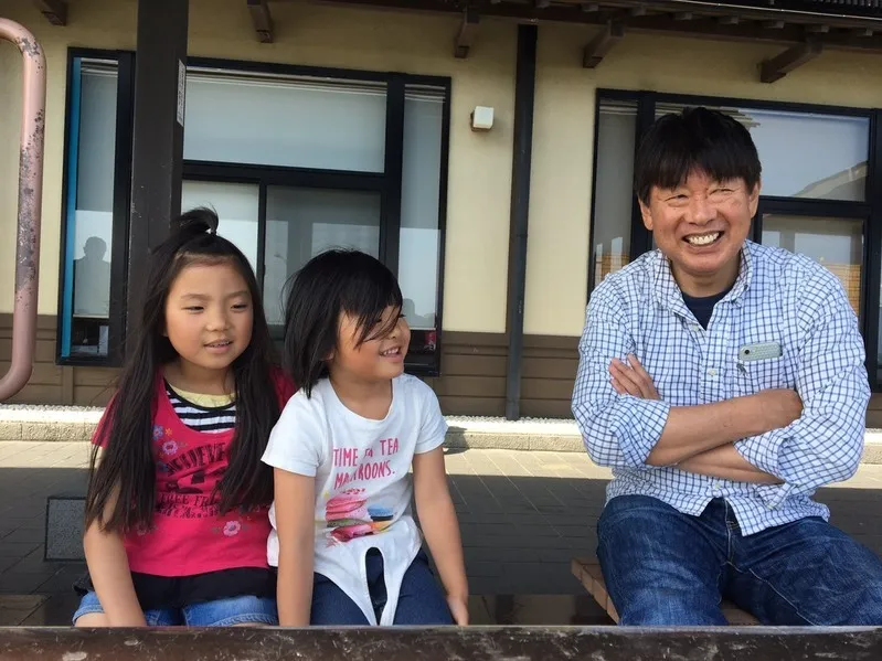 父親と娘2人が笑顔で映っている写真